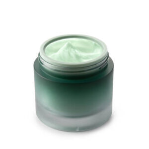 Green beauty cosmetic cream in green glass jar on white background.
